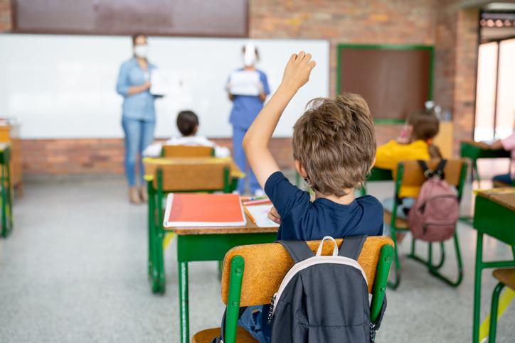 Boy at school asking questions to a nurse about the COVID-19 pandemic - education concepts